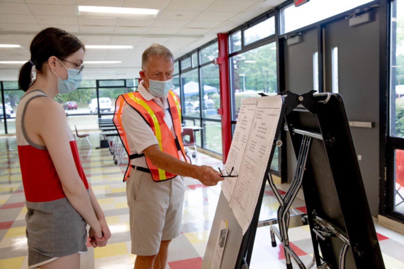 Henry Boulton, capacity monitor at a poll at Conard High School in West Hartford, gives an instruction to Elizabeth Davis, who voted for the first time on Tuesday.